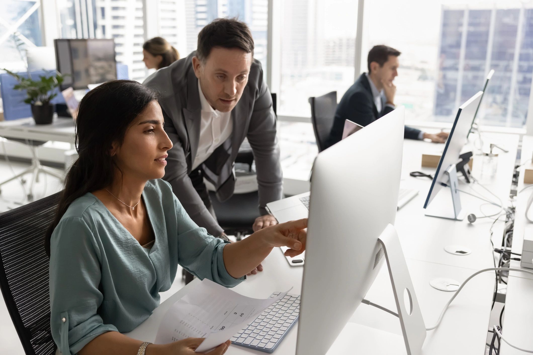 Two professionals reviewing work at a computer monitor